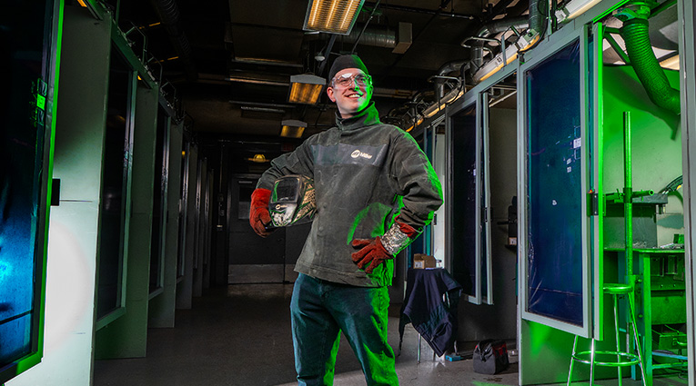 Young male standing with welding gear in hallway