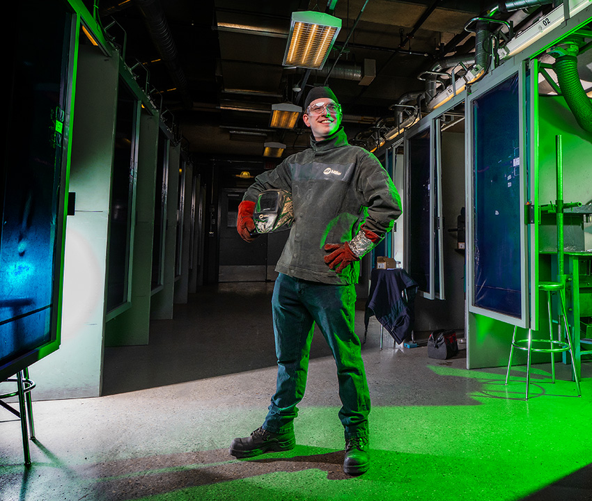 Young male standing with welding gear in hallway