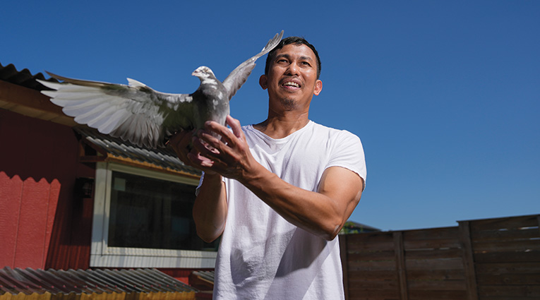 man in white tshirt holding a pigeon
