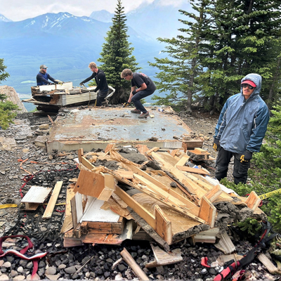 People dismantling a structure on a mountaintop.