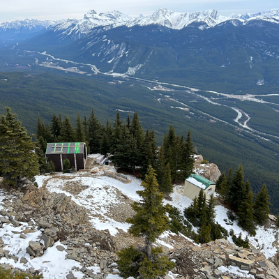 Cabins on a snowy mountain overlooking a wide valley.