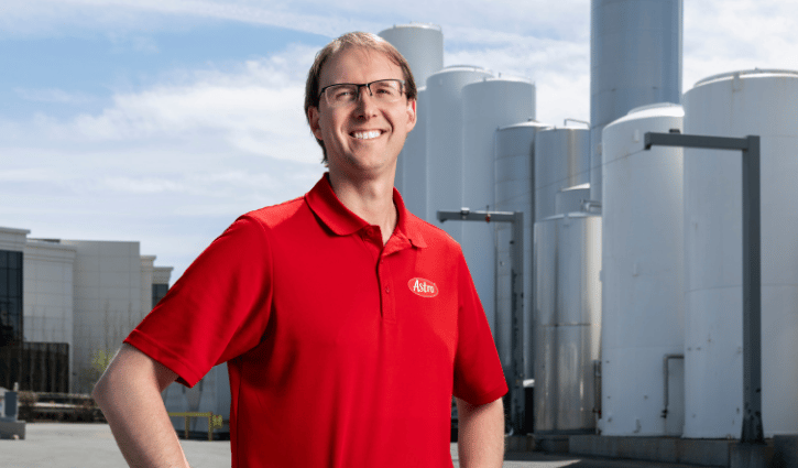 Man standing in work yard in front of silos