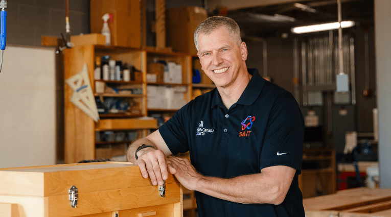 man in dark polo shirt smiling at camera