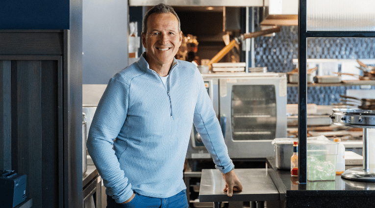 man in light blue half-zip sweater smiling