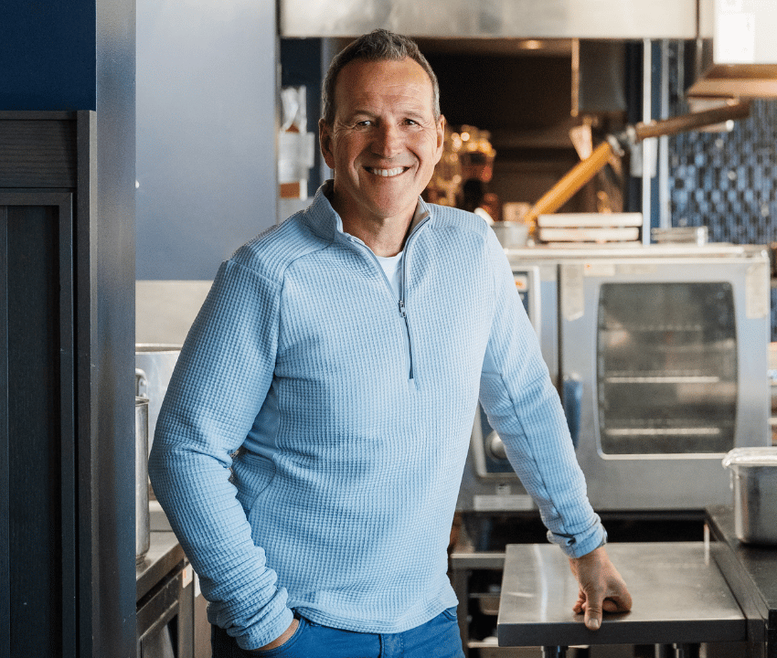 man in light blue half-zip sweater smiling