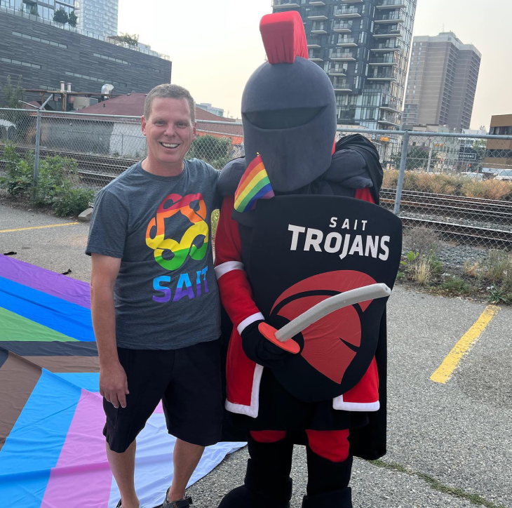 SAIT Vice President, Academic, Tom Bornhorst stands with the SAIT Trojans' mascot