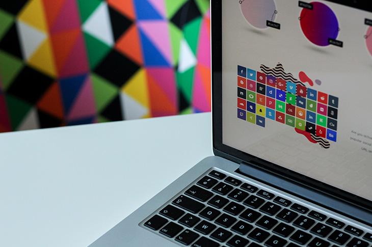 A laptop open on a table with the screen showing an interface with colourful icons