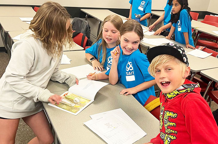 kids at a table smiling and wear bright coloured tshirts