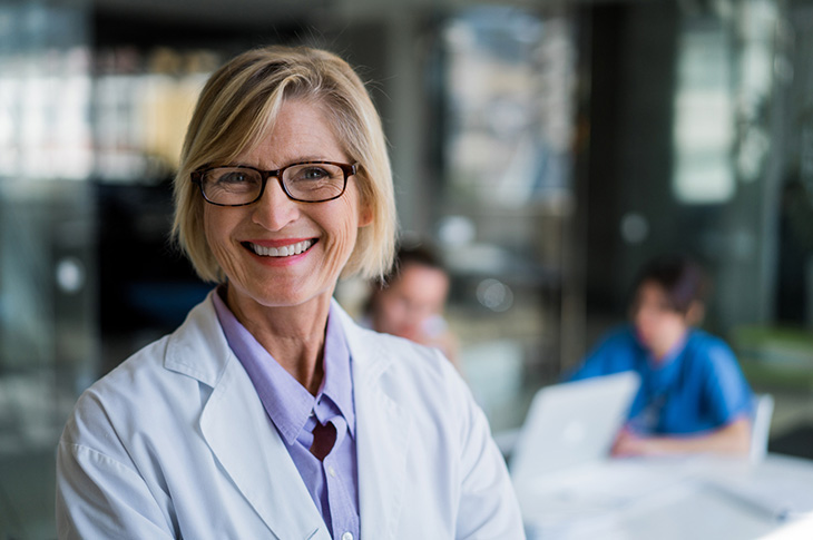 Person wearing a lab coat and smiling