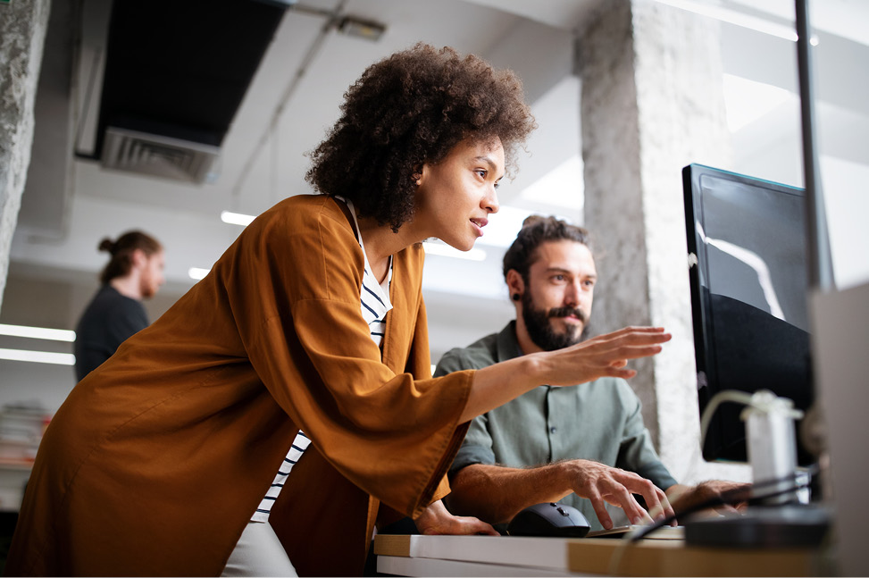 A female instructor looking at a computer monitor with a male student