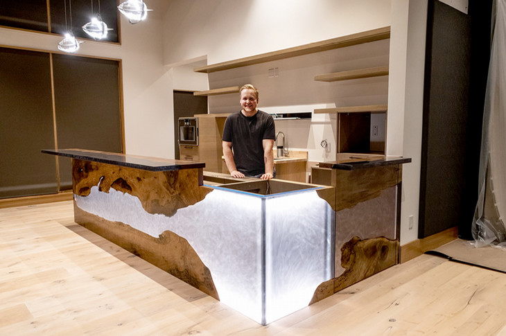 Two cabinetmakers stand beside finished cabinet projects.