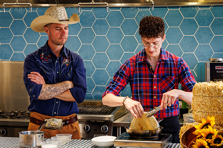 Chef Paul McGreevy watches as Chef Josh Grieman flips a pancake in a pan.