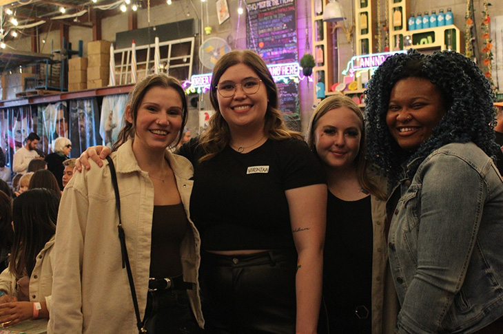 Four SAIT students stand together smiling at an event. 