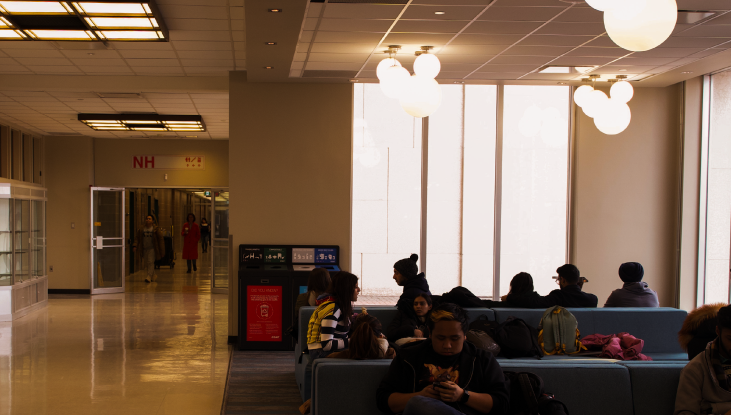 A shot of a student seating area in a building on SAIT’s campus with blue couches and students sitting on the furniture.