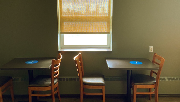 A shot of a staff lounge from a building on SAIT’s campus. Tables and chairs sit beneath a window, the wall is green.