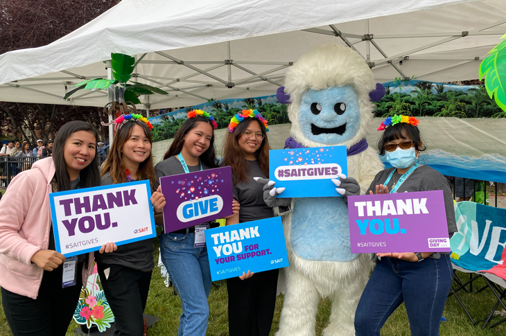 group of students holding thank you signs with Saitsa mascot yeti