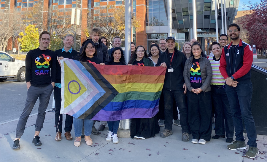 A group is holding a Pride flag before it is raised on campus for SAIT's Pride Week