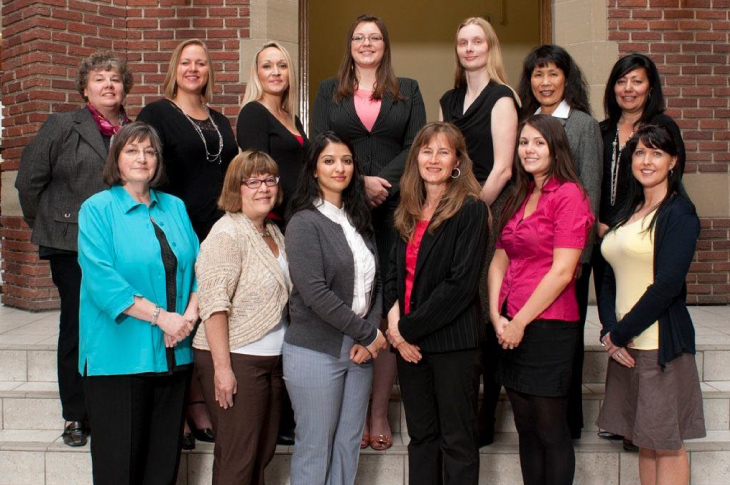 Jennifer Russell and a number of SAIT employees stand in front of Macdonald Hall inside the Irene Lewis Atrium for a group photo.