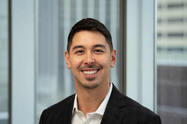 Kody Naka smiles at the camera in front of an indistinguishable background.