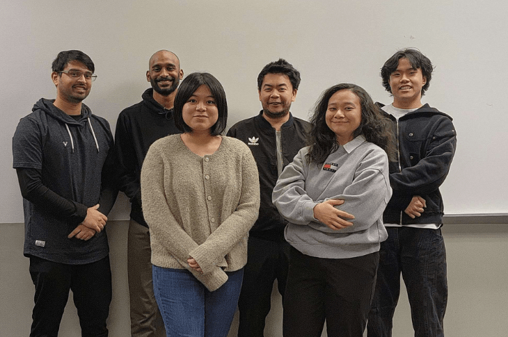 Six SAIT students stand in front of a blank grey wall. They are all smiling at the camera.