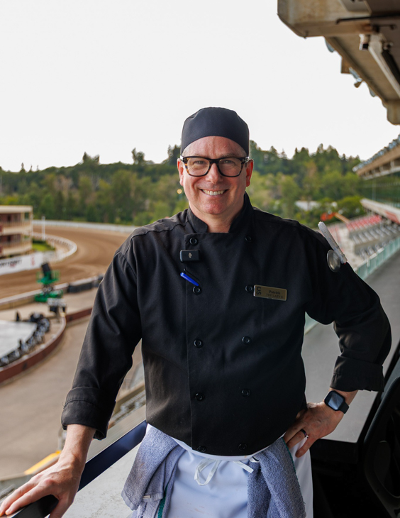 SAIT student smiles for a photo with the Calgary Stampede rodeo grounds in the background