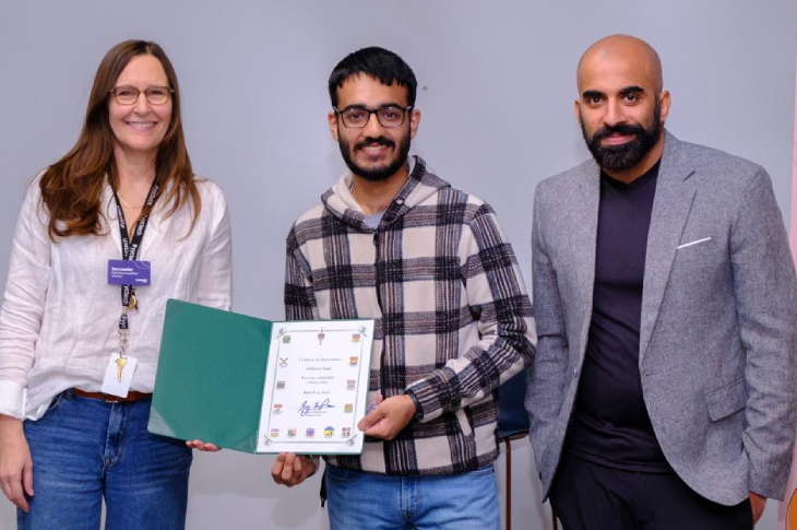 Sukhman Singh stands between two industry professionals. He is holding a certificate in his hands.