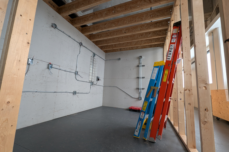 The interior of a pod in the shop, with wiring and ladders leaning up against the wooden frame of the pod.