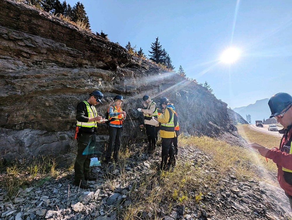 A group of people in safety vests standing on a rocky hill