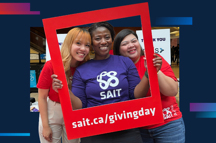 three females holding a picture frame that says sait.ca/givingday