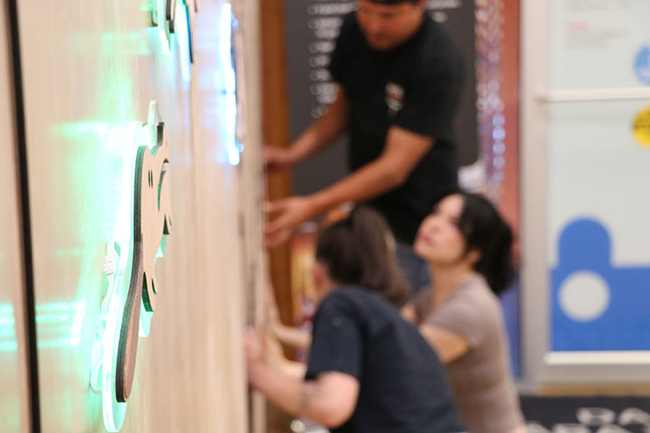 Natoysopoyiis mural made from engraved wood panels featuring pictographs from Blackfoot stories lit by LEDs