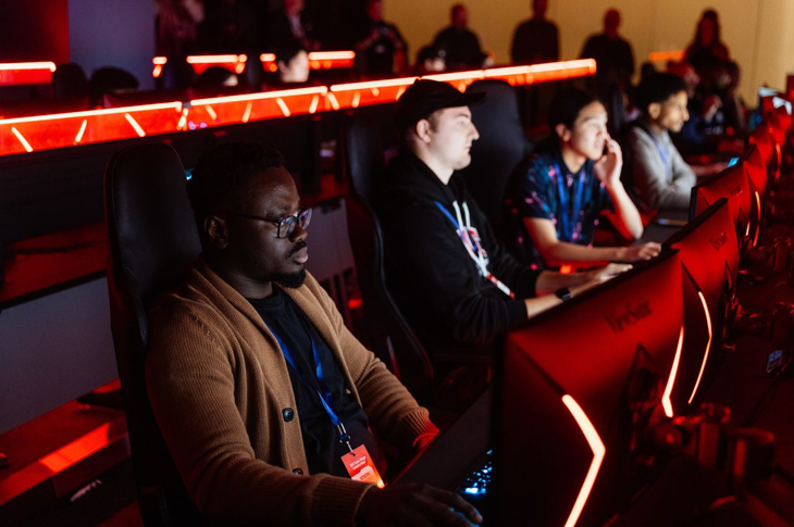 A group of people focused on their screens in SAIT's Cyber Range, illuminated by red lighting.