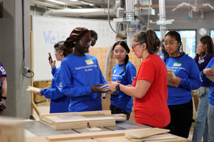 A carpentry instructor teaching students in a wood trades shop