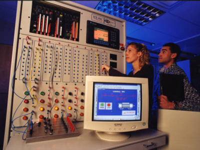 Two students standing in front of new equipment in AMOCO Centre, in 1998.