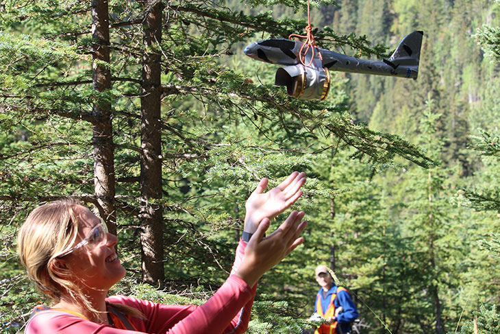 Olivia Zamrykut setting up a foam airplane in the trees