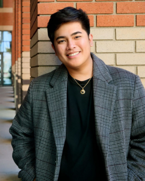 A headshot of Al Kim Lutao standing in front of a brick column.