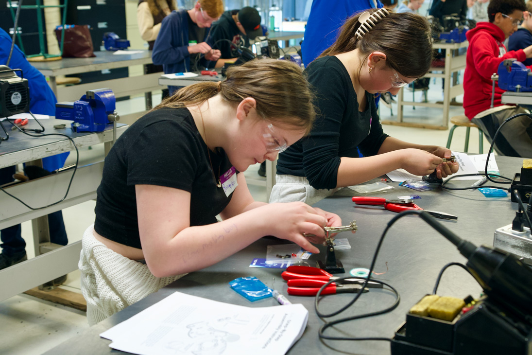 Two junior high students work with avionics in a lab.
