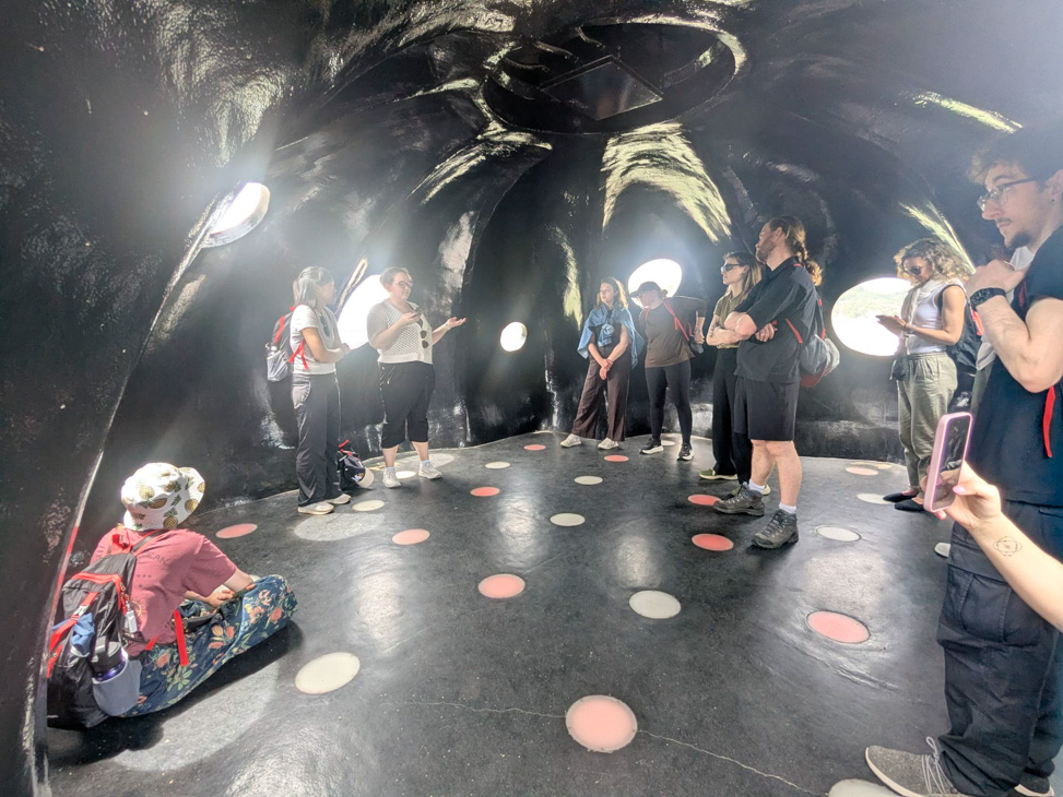 Group of people standing in a dark immersive space surrounded by circular lights and projections.