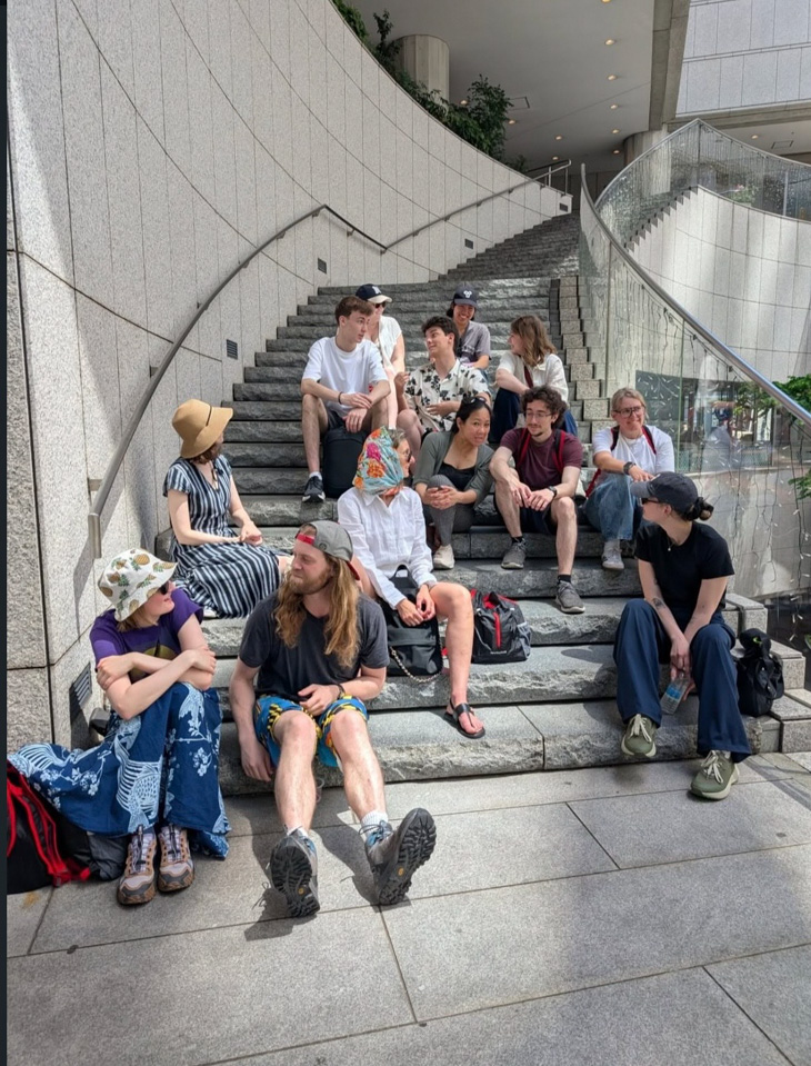 Group of people posing together on the steps of a modern building.