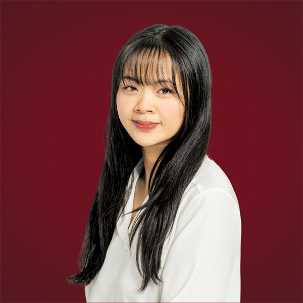 Tagan Trinh wearing a white blouse, set against a dark red background.