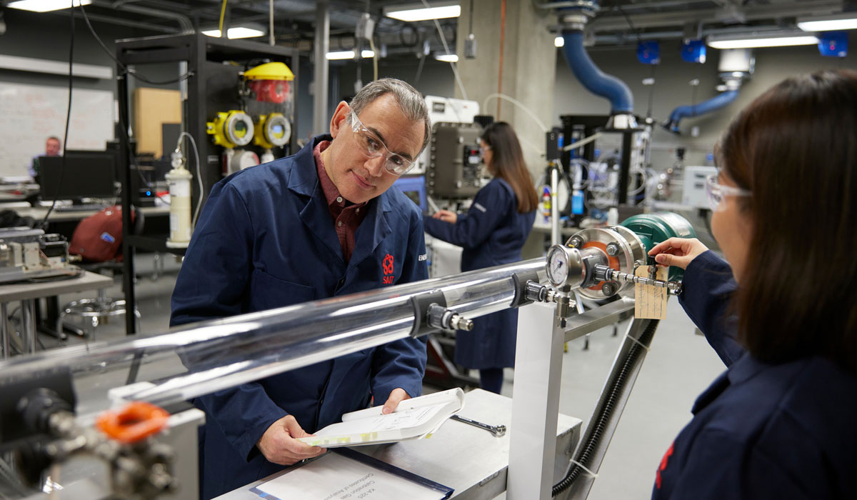 A professor supervising students as they conduct experiments in a modern engineering lab equipped with advanced technology.