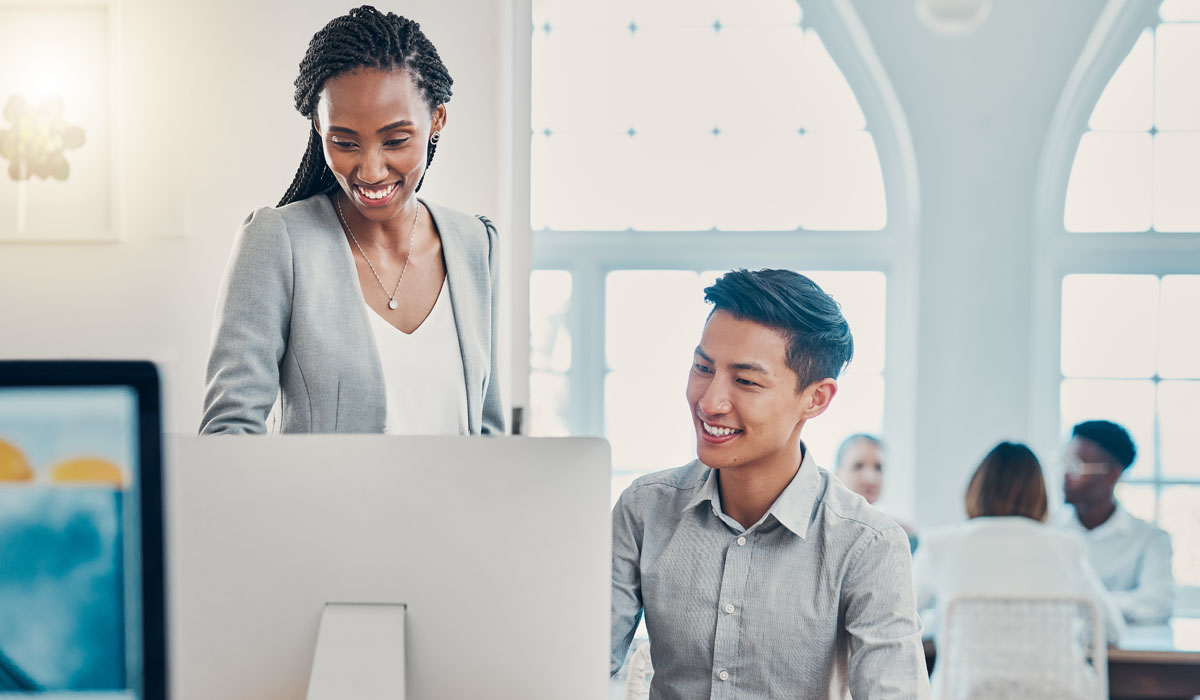 A cheerful professional woman interacts with a smiling male colleague at a modern workspace.