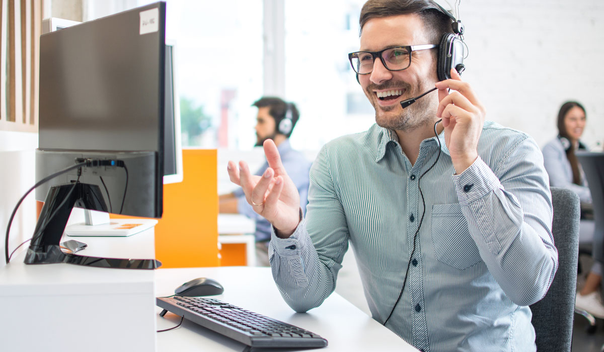 Customer service representative engaging with a caller using a headset at a modern office workstation.