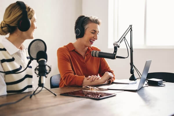 Two people wearing headphones speaking into microphones