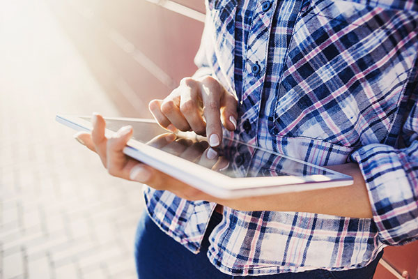 A close-up of a woman's hands using a tablet.