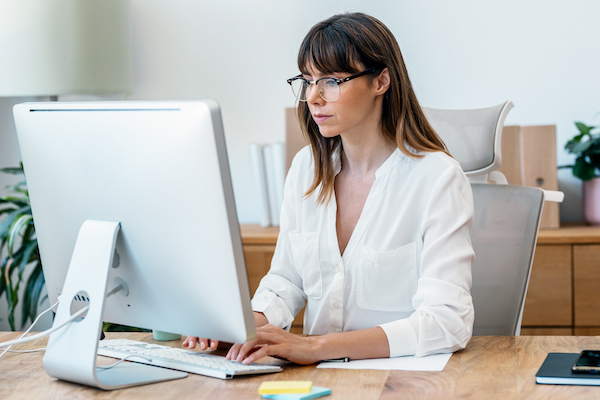 A woman works on a desktop computer in her office.