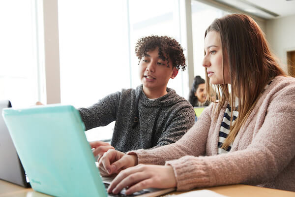 Two students working on a laptop 