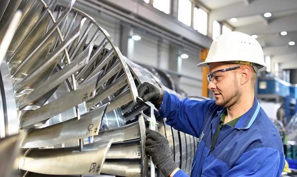 A person wearing a hardhat working on a turbine