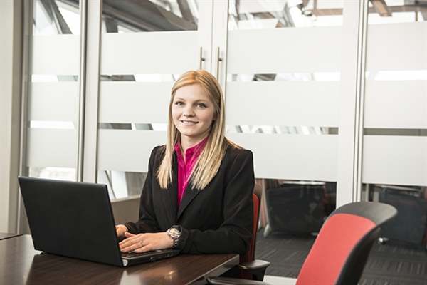 A woman with her hands on her laptop seated in a table in a conference room