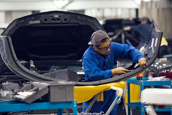 Man working on the bumper plate of a car. 