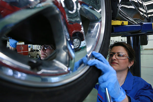 Student adjusting a tire on a car 